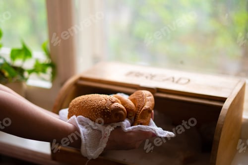 Preview: woman taking a bread loaf from a bread box in the kitchen at home