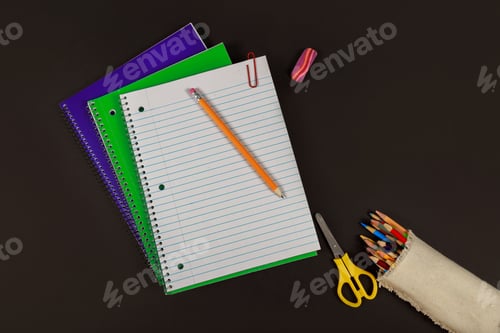 Preview: School and education supplies, notebooks, colored pencils on black table.