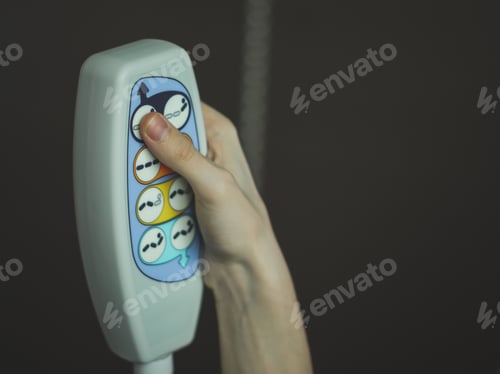 Preview: The hand of a young caucasian male holds a medical bedside remote control and presses a button