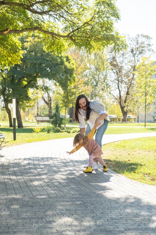 Preview: adult woman having fun, catch-up her child daughter in green park