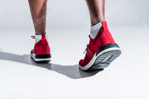 Preview: partial view of african american man in sports shoes on grey
