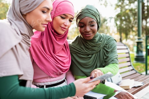 Preview: Muslim Female Showing Educational Application On Smartphone To Friends Outdoor