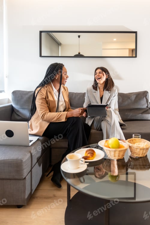Preview: Businesswomen laughing while working on a business trip in hotel room