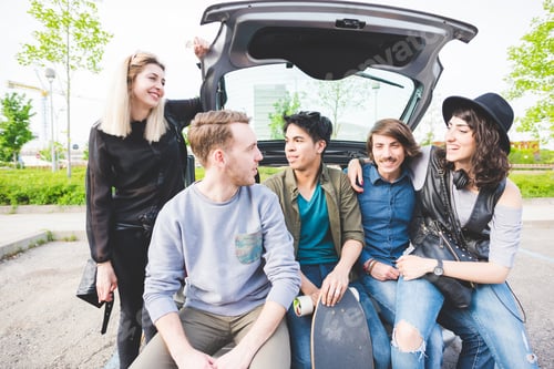 Preview: young multiethnic friends sitting in a trunk