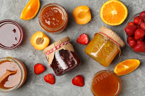 Preview: Glass jars with jam and ingredients on gray background, top view