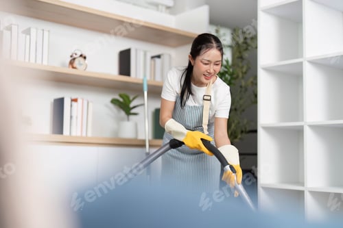 Preview: Home Cleaning. Joyful woman vacuuming while listening to music in a modern living room.