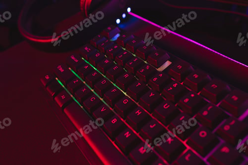 Preview: Composite of computer keyboard with video game accessories with copy space on neon background