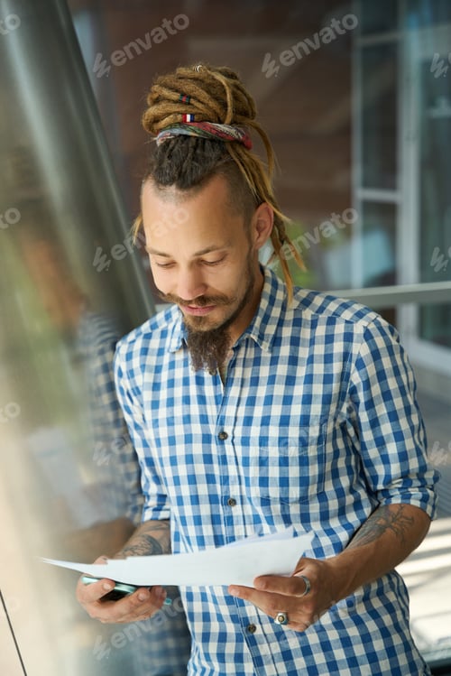 Preview: Guy is standing with papers and phone in front view window