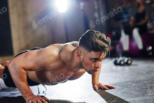 Preview: Serious man doing push ups in gym