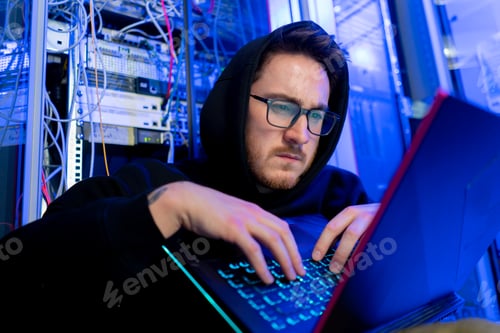 Preview: concentrated hooded hacker in data center hacking software system vulnerable cyber security server