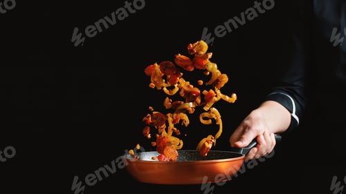 Preview: Chef cooking vegetables on a pan. Black background with copy space for your text. Freeze movements