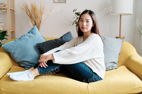 Preview: Young woman sitting on sofa