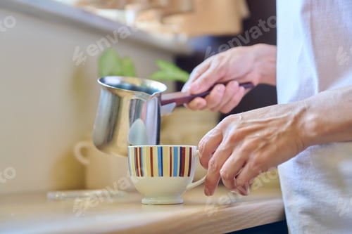 Preview: Close-up of a woman's hands preparing coffee in an iron cezve