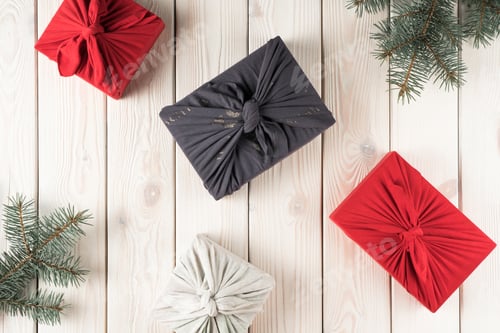 Preview: Composition of christmas presents in furoshiki package, top view. Spruce branches and gift boxes on