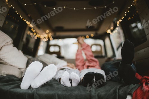 Preview: Family of parents and two kids having fun in a car decorated with Christmas festive lights.
