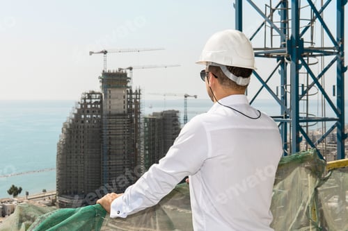 Preview: Confident architect or businessman wearing hard hat looking on a construction site