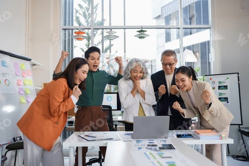 Preview: Excited business team celebrating success looking at laptop in the office