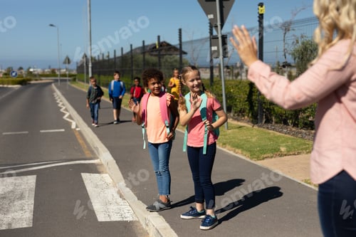 Preview: Female teacher with long blonde hair waving to schoolgirls