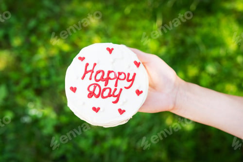 Preview: Bento cake with the inscription happy day and red hearts, a girl holds a cake in her hand on a