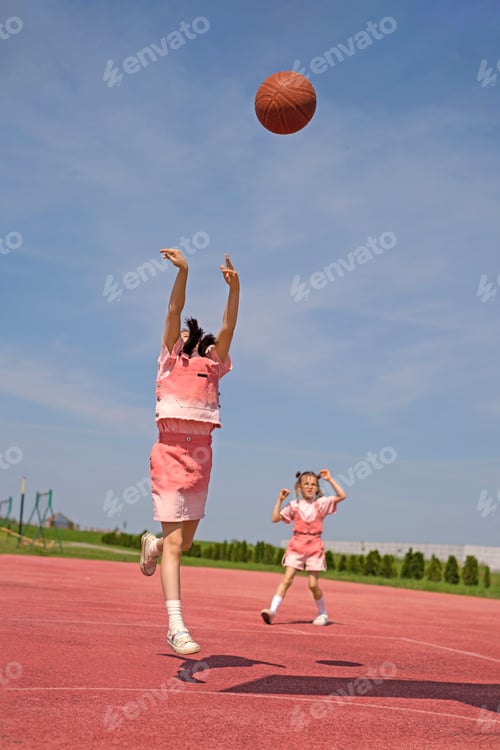 Preview: Girls on the sports court playing basketball on a sunny hot day.