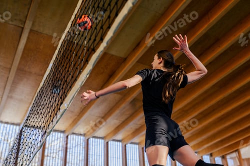 Preview: A young volleyball player is jumping and hitting a ball over the net.