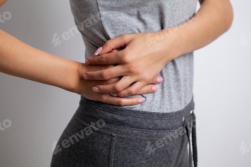 Preview: Attractive female person suffers from backache on gray background