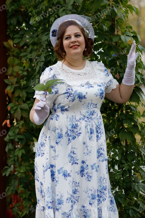 Preview: A woman in vintage clothes and a hat stands against the background of a fountain in an autumn park
