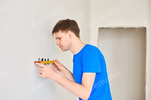Preview: Man using a spirit level to plumb a wall. Home renovation concept