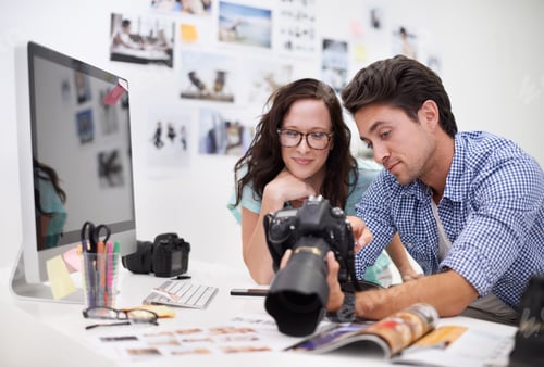 Preview: Two young photographers looking at photos on a digital camera in their studio