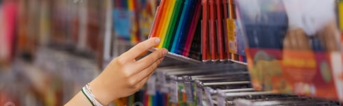 Preview: partial view of woman in beaded bracelets holding set of multicolored felt pens in blurred shop,