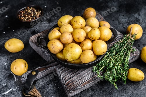 Preview: Young whole mini Potatoes in a pan. Black background. Top view