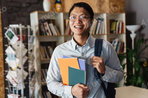 Preview: Image of happy asian man laughing and holding exercise books