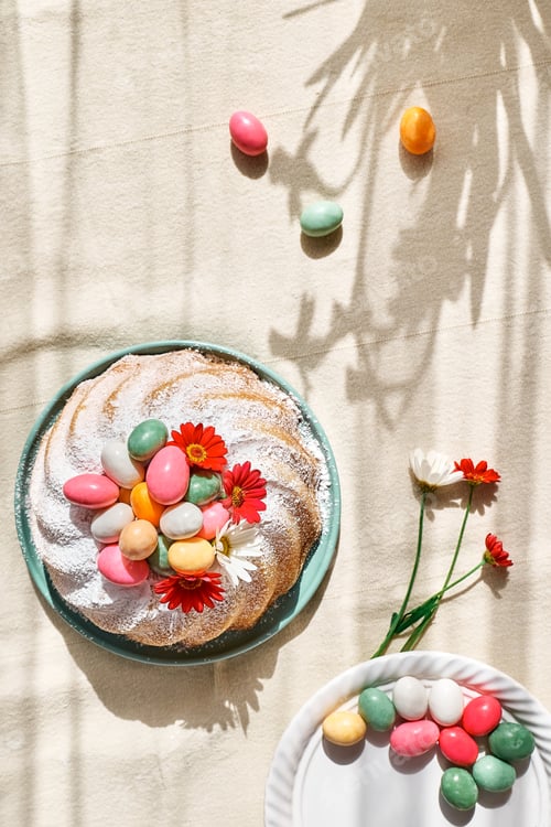 Preview: Easter cake decorated with icing sugar, small colorful chocolate eggs and daisy flowers.