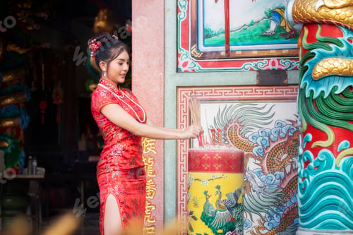 Preview: Celebrate Chinese New Year: Chinese woman in a red dress holding incense pay to Chinese god.