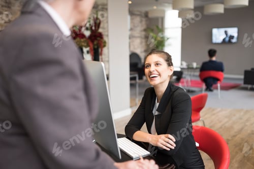 Preview: Young businesswoman and female colleague talking over office desk