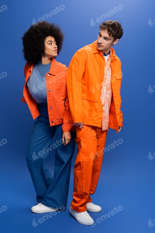 Preview: Interracial models in jackets looking at each other on blue background