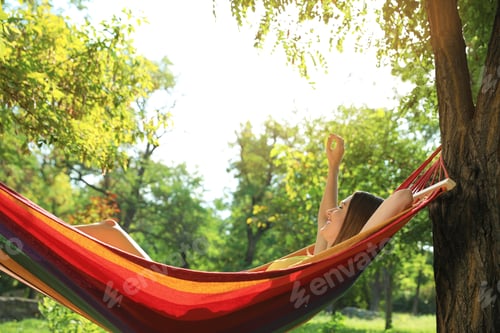 Preview: Young woman resting in comfortable hammock at green garden