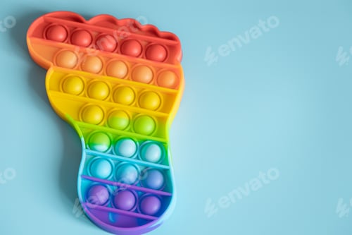Preview: Close up rainbow Pop it fidget toy on blue background copy space.