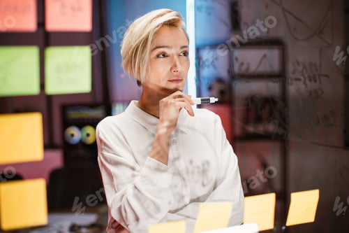 Preview: Businesswoman working on new project strategy, standing near glass board with sticky notes