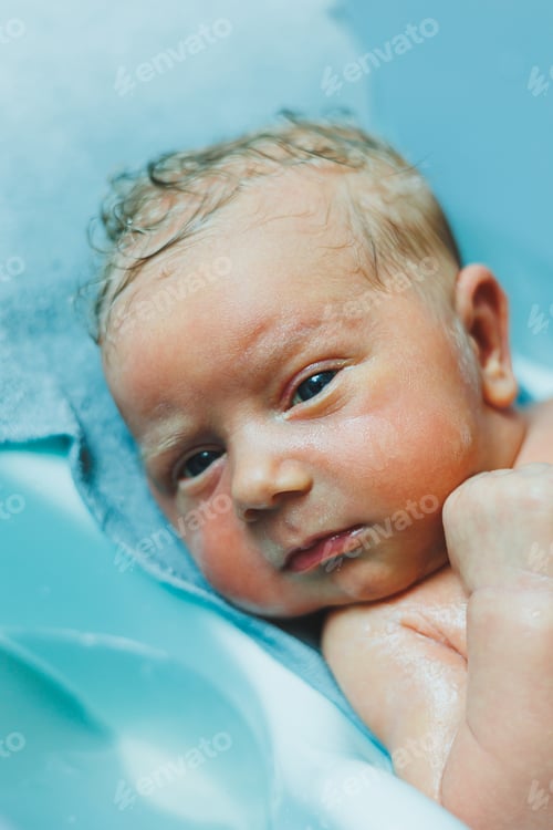 Preview: A newborn baby lies in a bathtub, the first bathing of a newborn baby. Bathing a newborn baby.