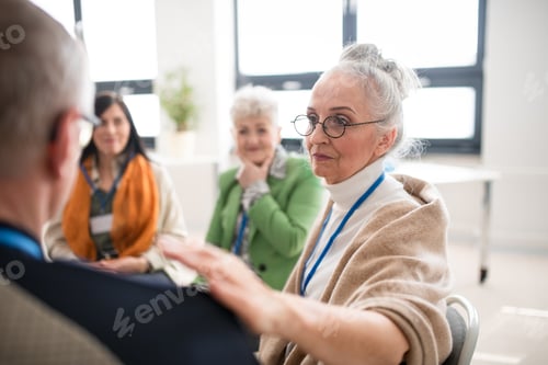 Preview: Group of senior people sitting in circle during therapy session, woman consoling depressed man