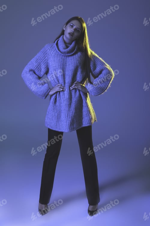 Preview: stylish model posing in warm trendy sweater, on blue
