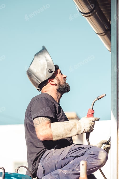 Preview: worker with a soldering iron in hand and a protective helmet