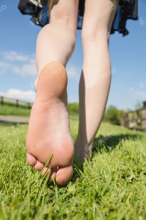 Preview: Womans feet walking away on grass on a sunny day in the countryside