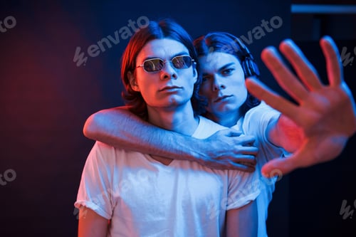 Preview: Our territory. Portrait of twin brothers. Studio shot in dark studio with neon light