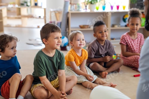 Preview: Group of small nursery school children sitting on floor indoors in classroom