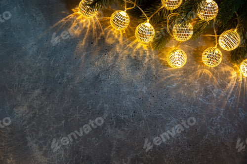 Preview: Christmas fir branch with decorative garlands balls glowing light on grey texture background