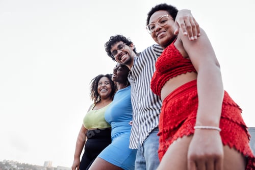 Preview: Four smiling mixed race friends standing and looking down at camera