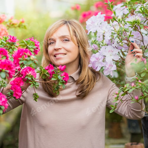 Preview: Beautiful woman watering plants and gardening in greenhouse.
