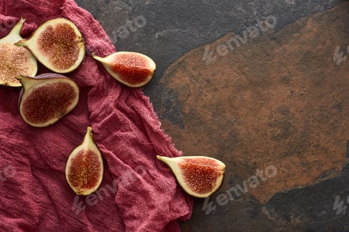 Preview: Top View of Ripe Cut Delicious Figs on Rustic Red Cloth on Stone Background